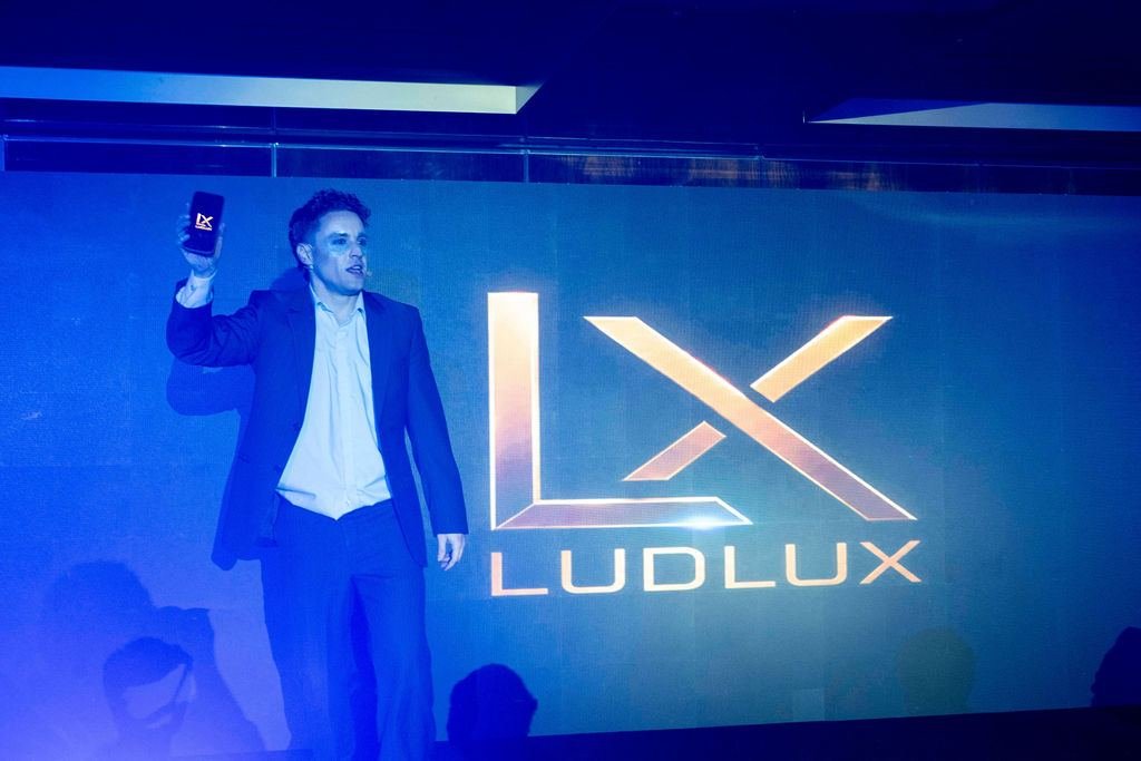 Condutor da experiência no palco, com a marca LudLux ao fundo